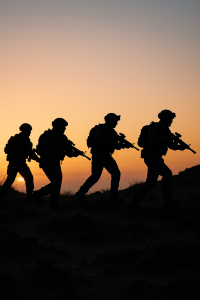 Silhouetted special forces soldiers advancing across rough ground at sunrise, symbolising precision missions and global deployment.