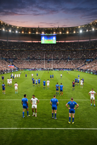 Rugby players standing across the pitch after the final whistle of a Six Nations match at dusk.